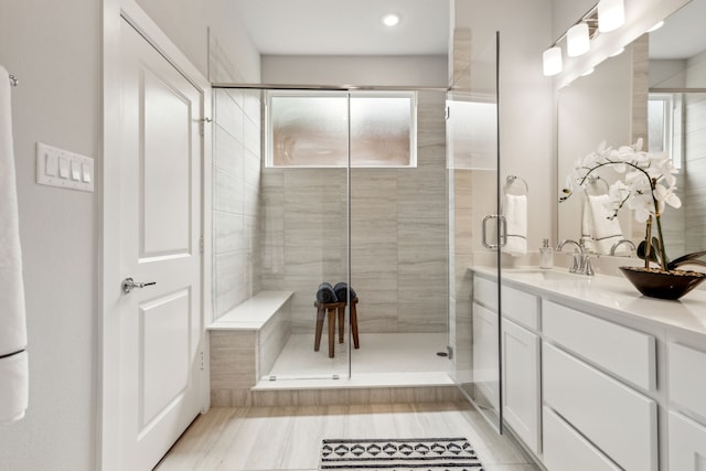 bathroom featuring a shower with shower door and vanity