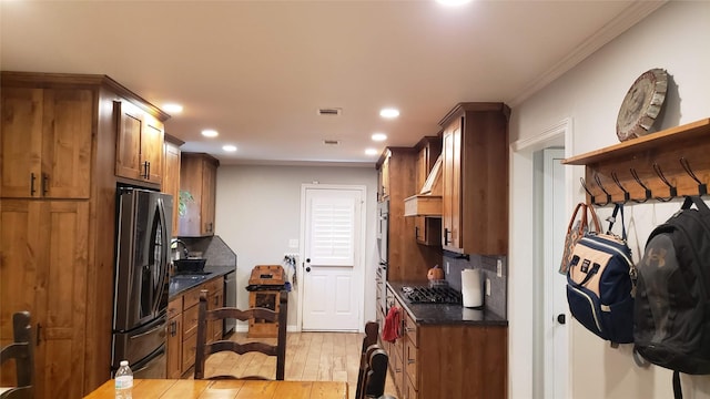 kitchen with backsplash, ornamental molding, stainless steel appliances, sink, and light hardwood / wood-style flooring