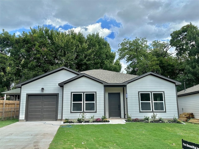 ranch-style house featuring a front yard, fence, driveway, roof with shingles, and an attached garage