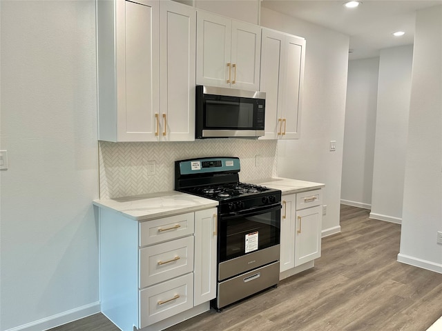 kitchen with stainless steel appliances, decorative backsplash, and light hardwood / wood-style floors