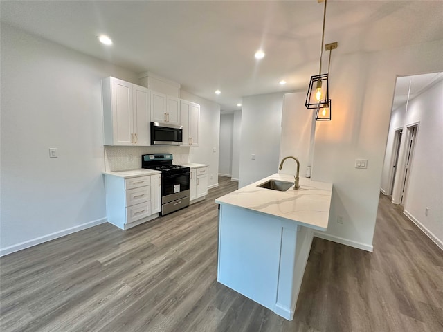 kitchen featuring hardwood / wood-style flooring, appliances with stainless steel finishes, white cabinetry, sink, and pendant lighting