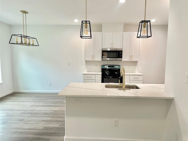 kitchen featuring stainless steel microwave, backsplash, light stone countertops, gas stove, and a sink