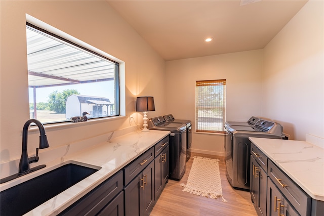 kitchen featuring light stone counters, light hardwood / wood-style flooring, washing machine and clothes dryer, and sink