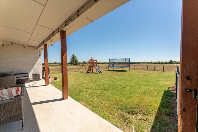 view of yard featuring a trampoline, a playground, and a patio area