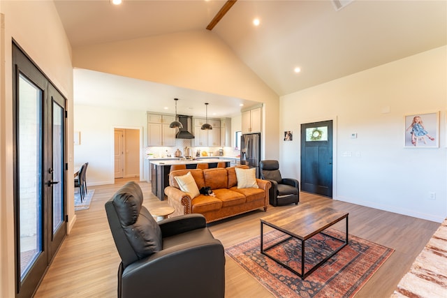 living room with plenty of natural light, high vaulted ceiling, and light hardwood / wood-style floors