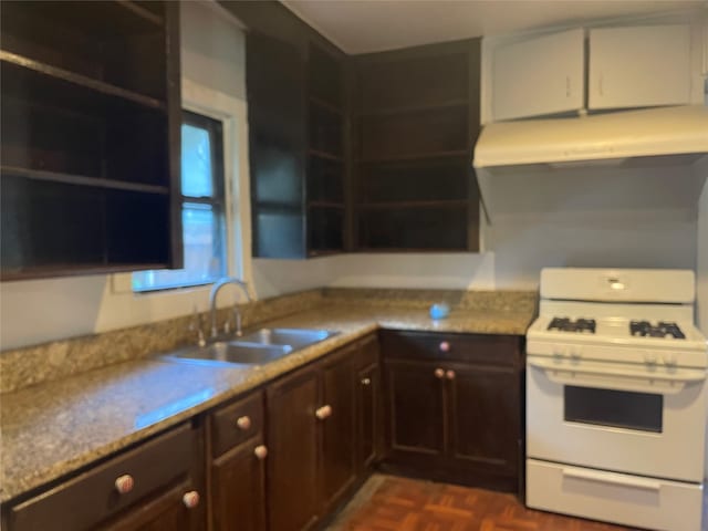 kitchen with white gas stove, sink, dark parquet flooring, and light stone countertops