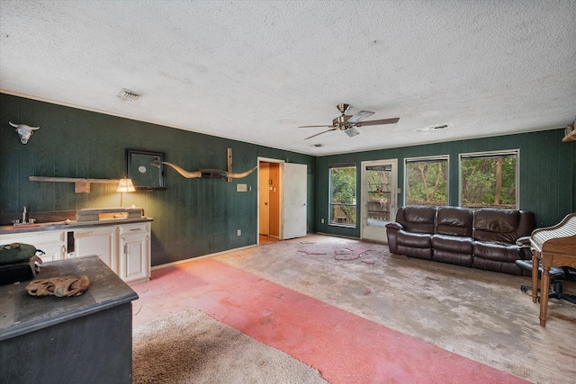 living room with ceiling fan, sink, and a textured ceiling