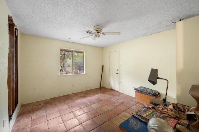 interior space with a textured ceiling, ceiling fan, and tile patterned floors