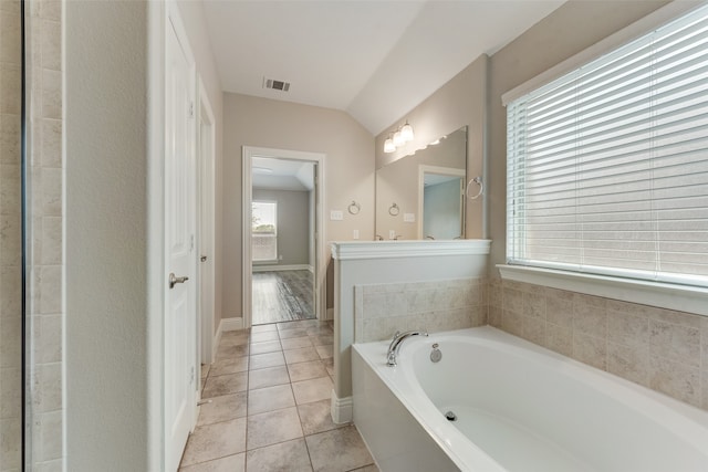 bathroom with tile patterned flooring, a bathing tub, and lofted ceiling