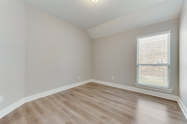 spare room featuring lofted ceiling and light hardwood / wood-style flooring