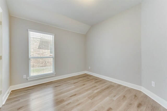 spare room with lofted ceiling and light hardwood / wood-style flooring