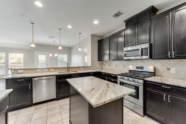 kitchen with backsplash, a center island, appliances with stainless steel finishes, sink, and pendant lighting