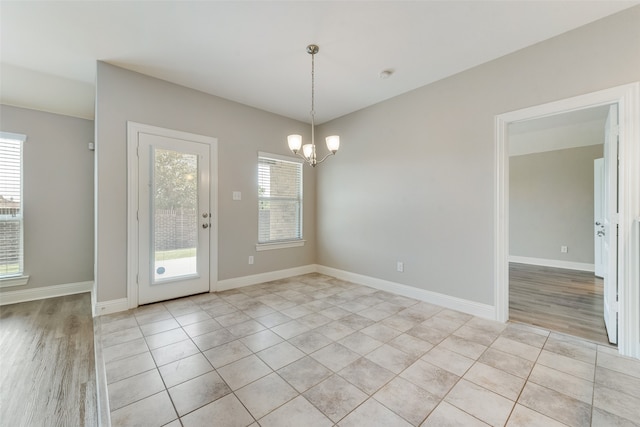 spare room with light wood-type flooring and a notable chandelier