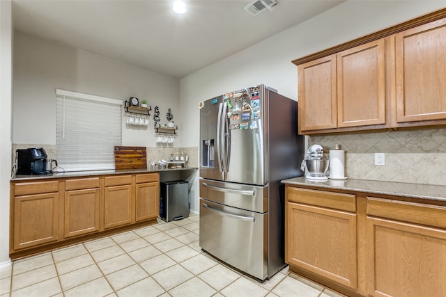 kitchen featuring stainless steel fridge, decorative backsplash, and light tile patterned flooring