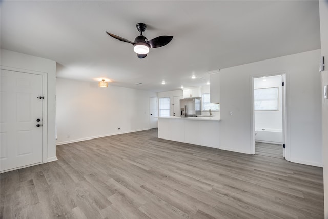 unfurnished living room featuring light hardwood / wood-style flooring, sink, and ceiling fan