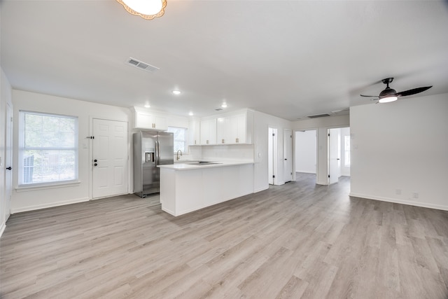 kitchen with white cabinets, light hardwood / wood-style floors, kitchen peninsula, stainless steel refrigerator with ice dispenser, and ceiling fan