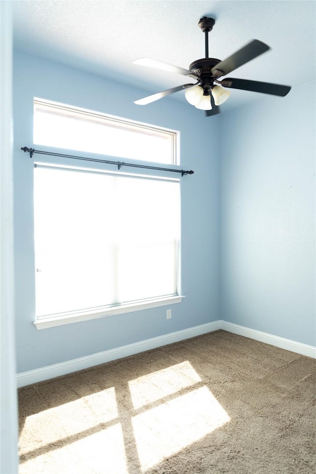 spare room featuring baseboards, a ceiling fan, carpet flooring, and a wealth of natural light