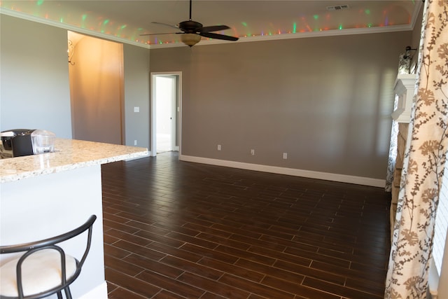 kitchen with ceiling fan, ornamental molding, light stone countertops, and dark hardwood / wood-style flooring