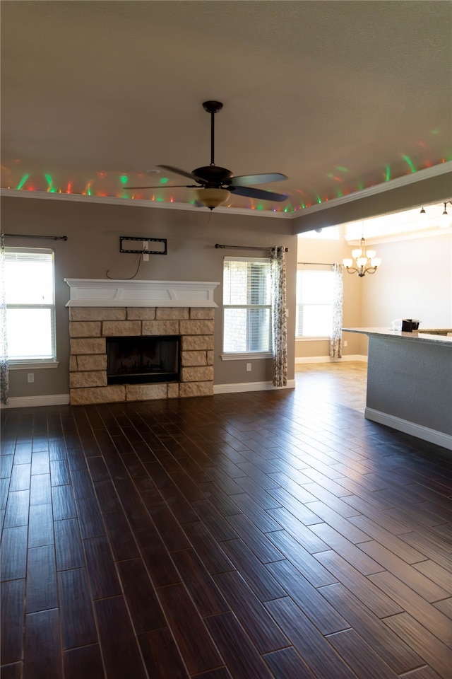 unfurnished living room featuring ceiling fan, a stone fireplace, dark wood-type flooring, and a wealth of natural light