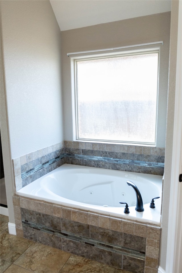 bathroom with tile patterned flooring, a relaxing tiled tub, and a healthy amount of sunlight