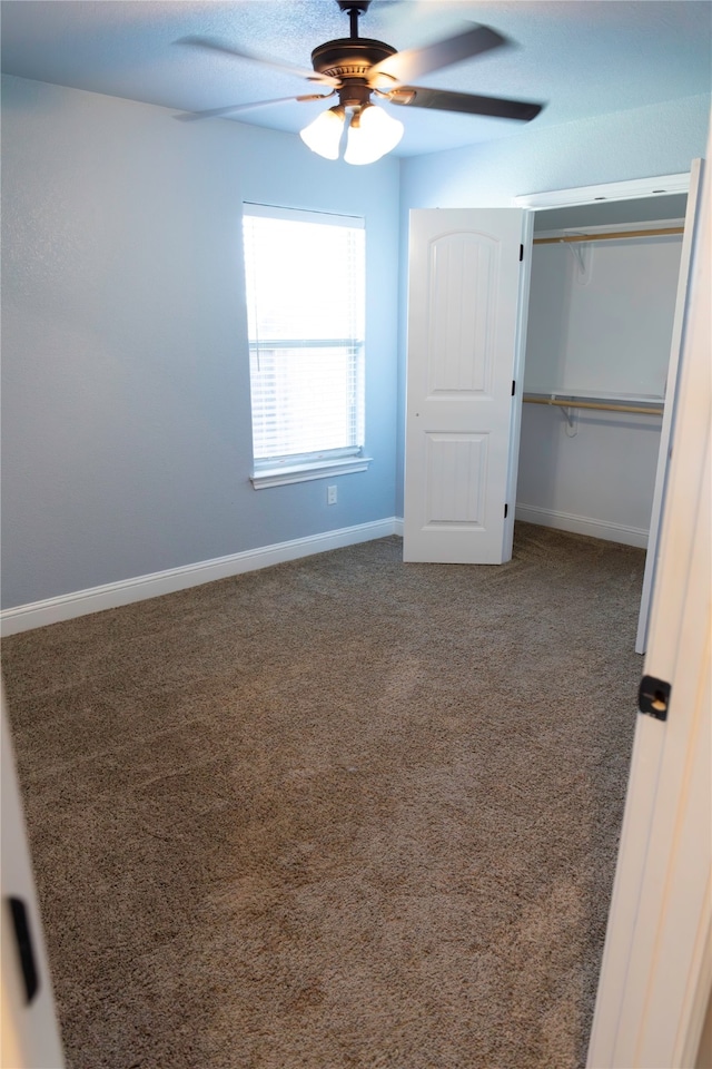 unfurnished bedroom with a closet, dark colored carpet, and ceiling fan