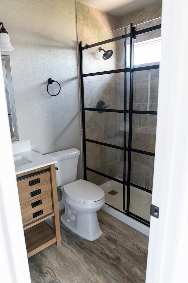 bathroom featuring a shower with door, hardwood / wood-style floors, vanity, and toilet