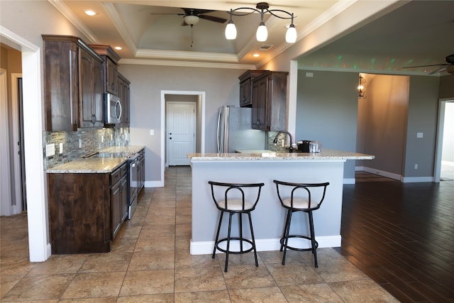 kitchen with tasteful backsplash, light hardwood / wood-style flooring, appliances with stainless steel finishes, light stone countertops, and crown molding