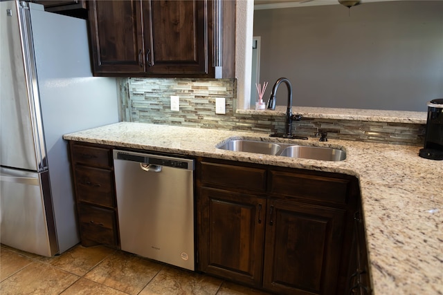 kitchen featuring tasteful backsplash, dark brown cabinets, sink, light stone counters, and stainless steel appliances