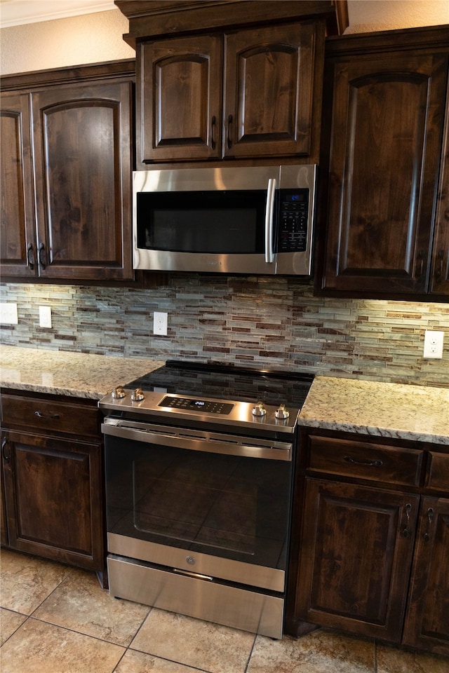 kitchen featuring dark brown cabinetry, decorative backsplash, light stone countertops, appliances with stainless steel finishes, and light tile patterned floors