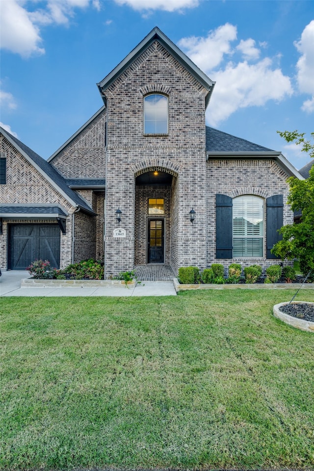 french country inspired facade featuring a garage and a front lawn