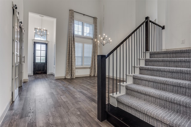 foyer entrance with a notable chandelier, a high ceiling, dark hardwood / wood-style floors, and a barn door