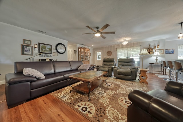 living room featuring ceiling fan, ornamental molding, and hardwood / wood-style flooring