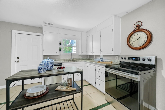 kitchen with light tile patterned floors, sink, white cabinetry, and stainless steel range with electric stovetop