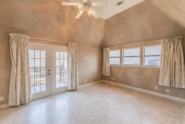 spare room with a towering ceiling, a wealth of natural light, ceiling fan, and french doors