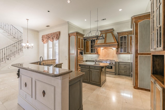 kitchen featuring appliances with stainless steel finishes, sink, hanging light fixtures, a kitchen island with sink, and custom range hood