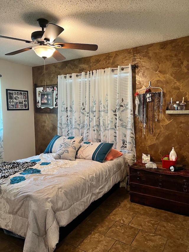 bedroom with stone finish floor, a ceiling fan, and a textured ceiling