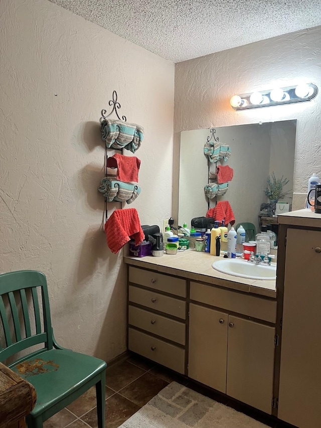 bathroom with tile patterned flooring, a textured ceiling, vanity, and a textured wall