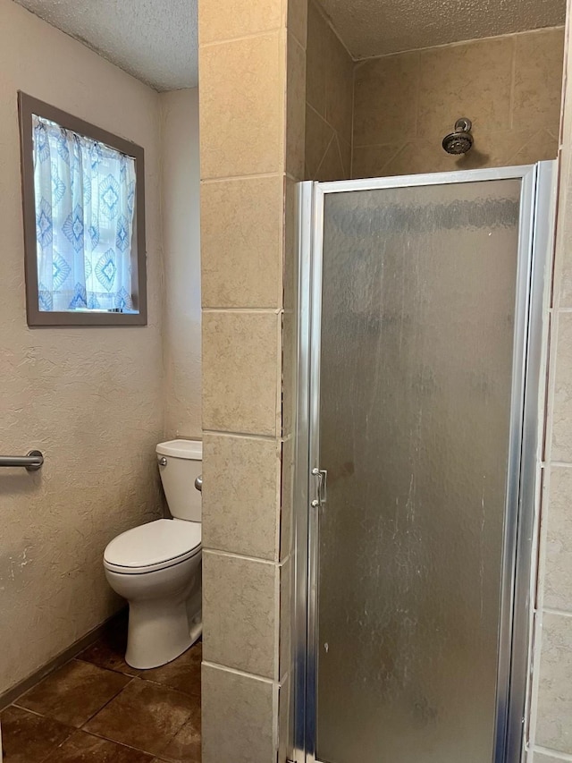 full bath with a textured ceiling, a shower stall, and toilet