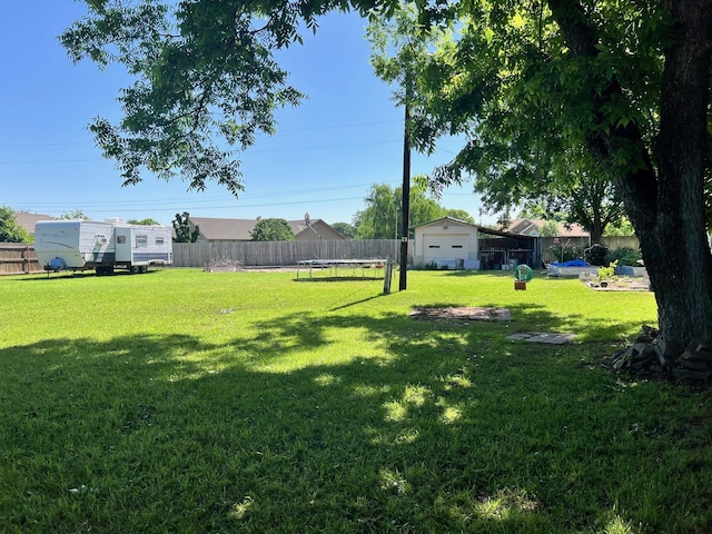 view of yard featuring an outbuilding, a trampoline, and a fenced backyard