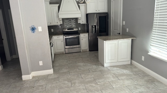 kitchen with appliances with stainless steel finishes, white cabinetry, premium range hood, light tile patterned flooring, and decorative backsplash