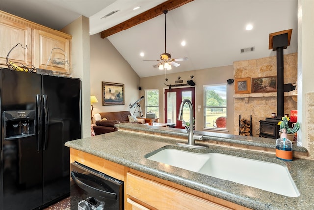 kitchen featuring lofted ceiling with beams, a wood stove, sink, black appliances, and ceiling fan