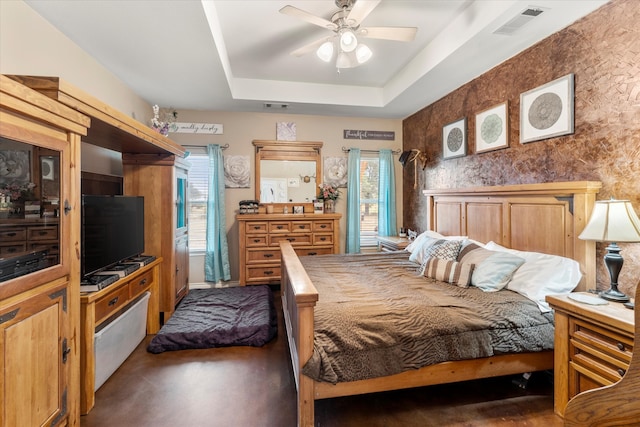 bedroom with multiple windows, ceiling fan, and a tray ceiling