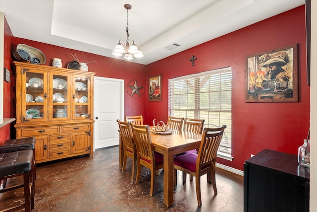 dining area with a tray ceiling and a chandelier