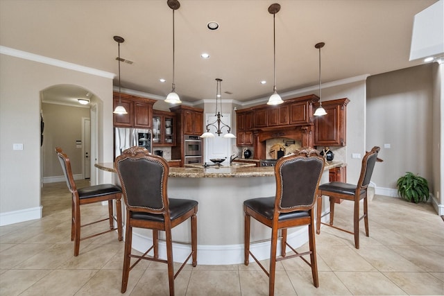 kitchen with arched walkways, light stone counters, light tile patterned flooring, visible vents, and pendant lighting