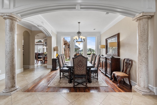 dining room featuring an inviting chandelier, light hardwood / wood-style flooring, ornamental molding, and decorative columns