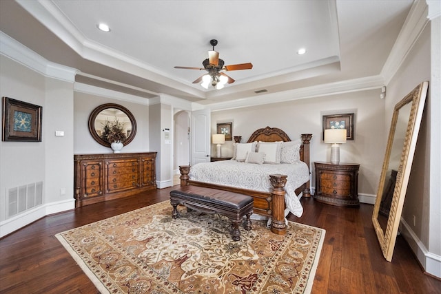 bedroom featuring arched walkways, dark wood-type flooring, a raised ceiling, and visible vents