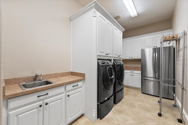 washroom featuring cabinets, sink, washing machine and dryer, and light tile patterned floors