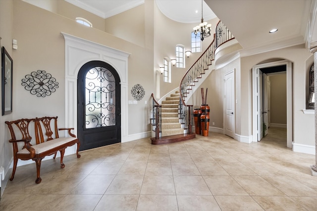 tiled foyer featuring crown molding, a high ceiling, and an inviting chandelier