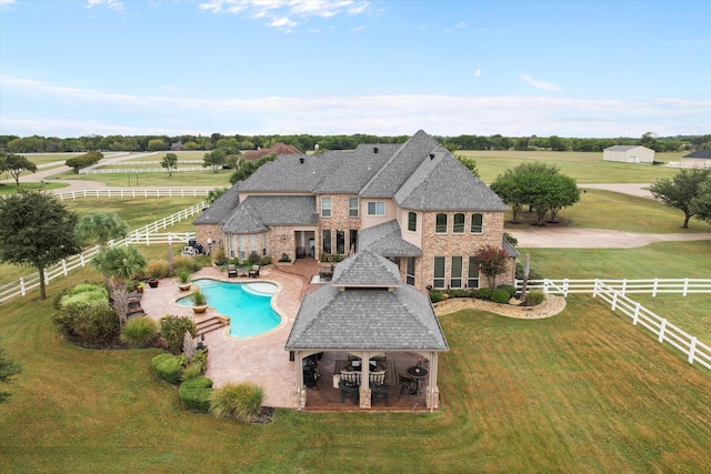 view of swimming pool featuring a patio area, a yard, and a rural view