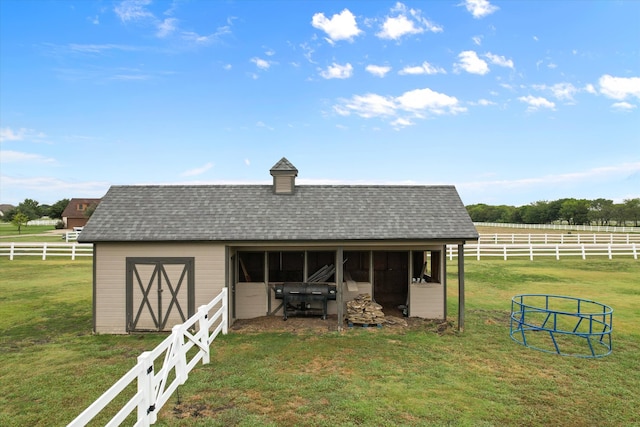 view of outdoor structure featuring a rural view and a lawn